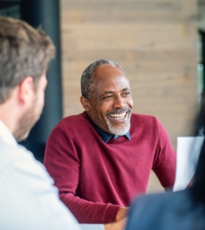 Man laughing with colleagues in meeting