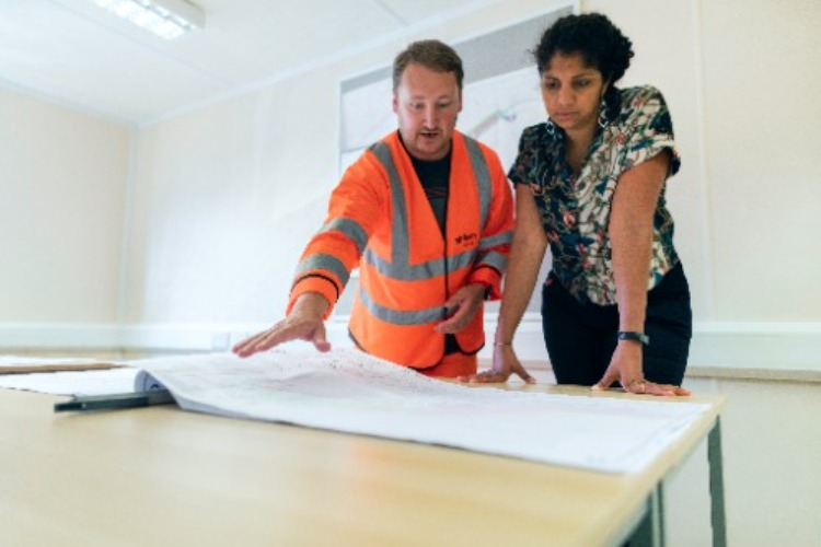 Man in hi vis workwear discussing building plans with female colleague