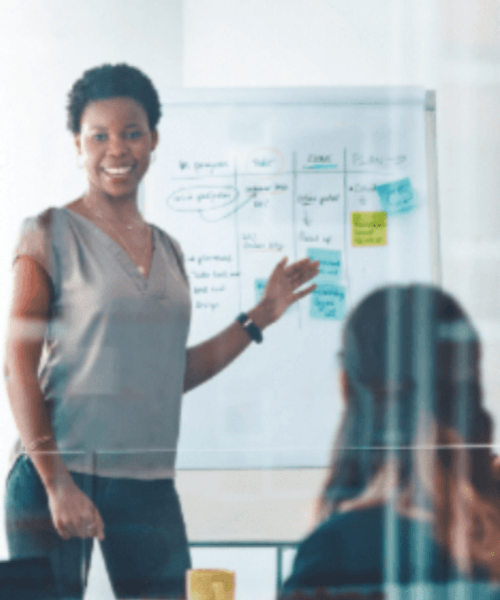 Woman standing to present in front of colleagues in meeting